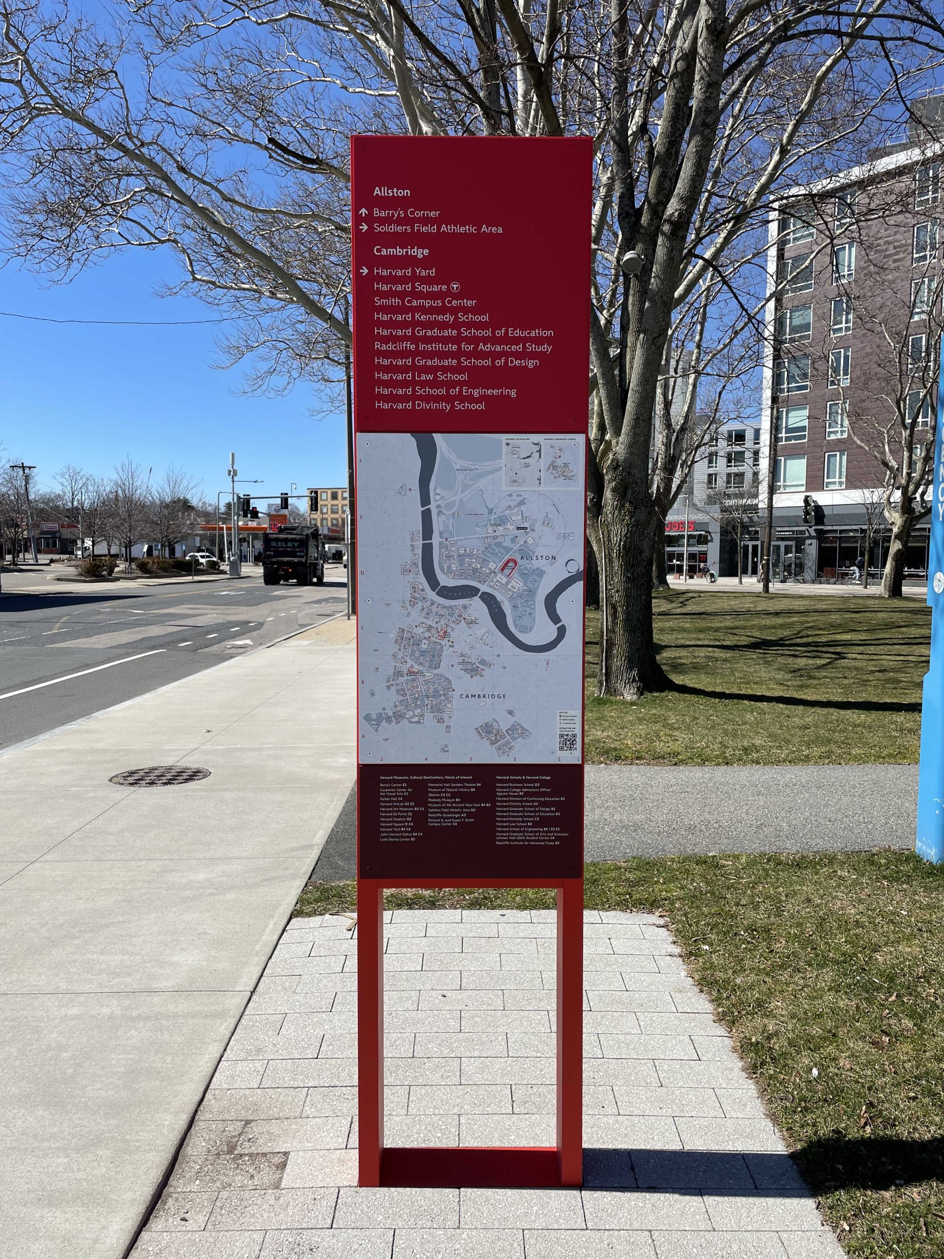 A red directional marker with directions and a map of Harvard University found in Allston