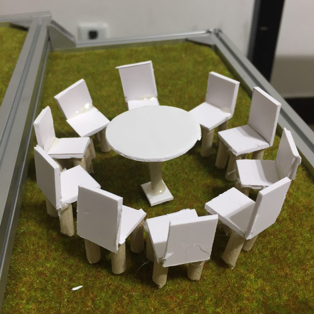 A round table surrounded by a near dozen chairs, in our house model