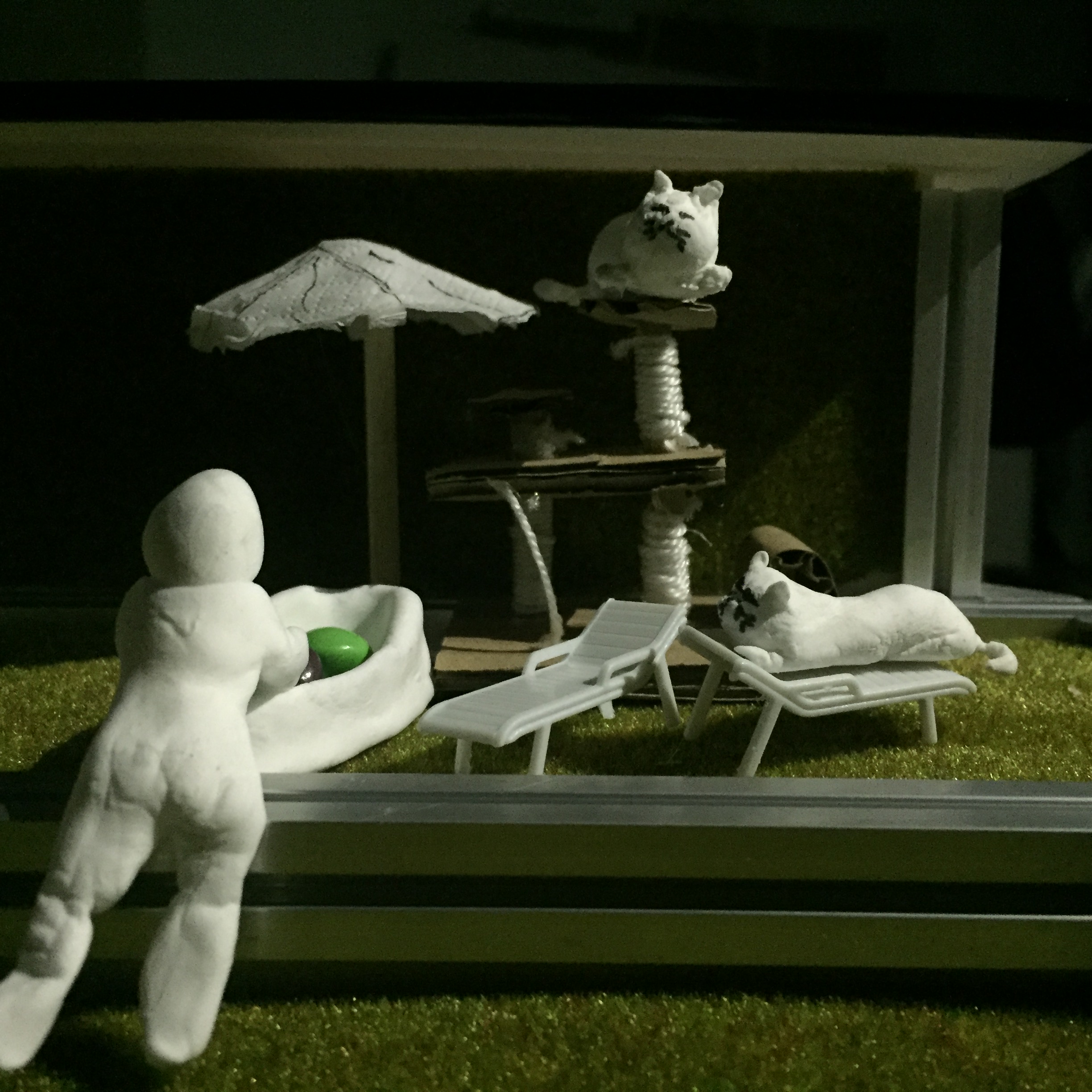 Close-up view of a mini house model showing the homeowner and their two cats